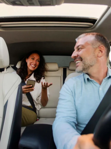 Professional photo of the inside of taxi cab where the taxi driver is conversing with the middle aged passenger customer