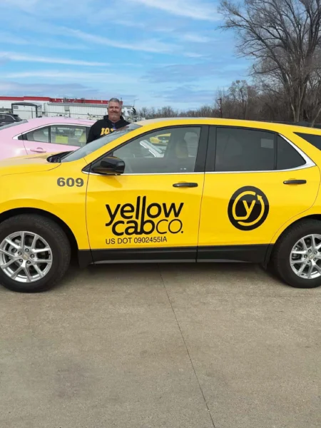 Clean and professional photo of the side of a yellow taxi cab SUV with a black decal on the side that saids 
