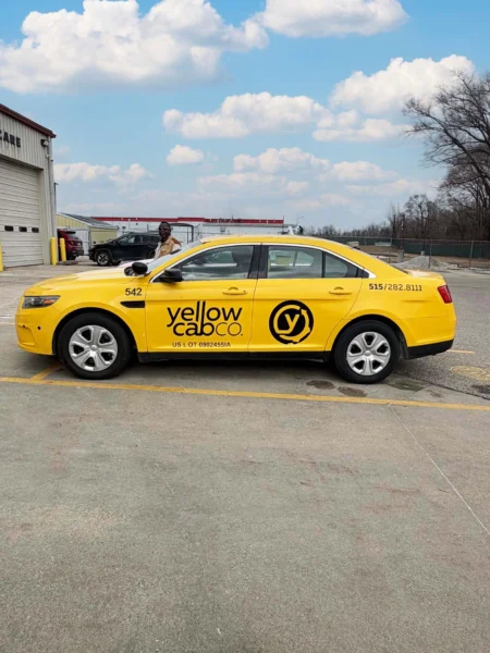 Clean and professional photo of a yellow taxi cab with a black decal on the side that saids 